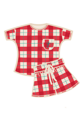 A two-piece teen pyjama set featuring a short-sleeve top and matching shorts in a red, white, and green tartan, with a cream-colored collar, pocket, and drawstring. Made from organic cotton